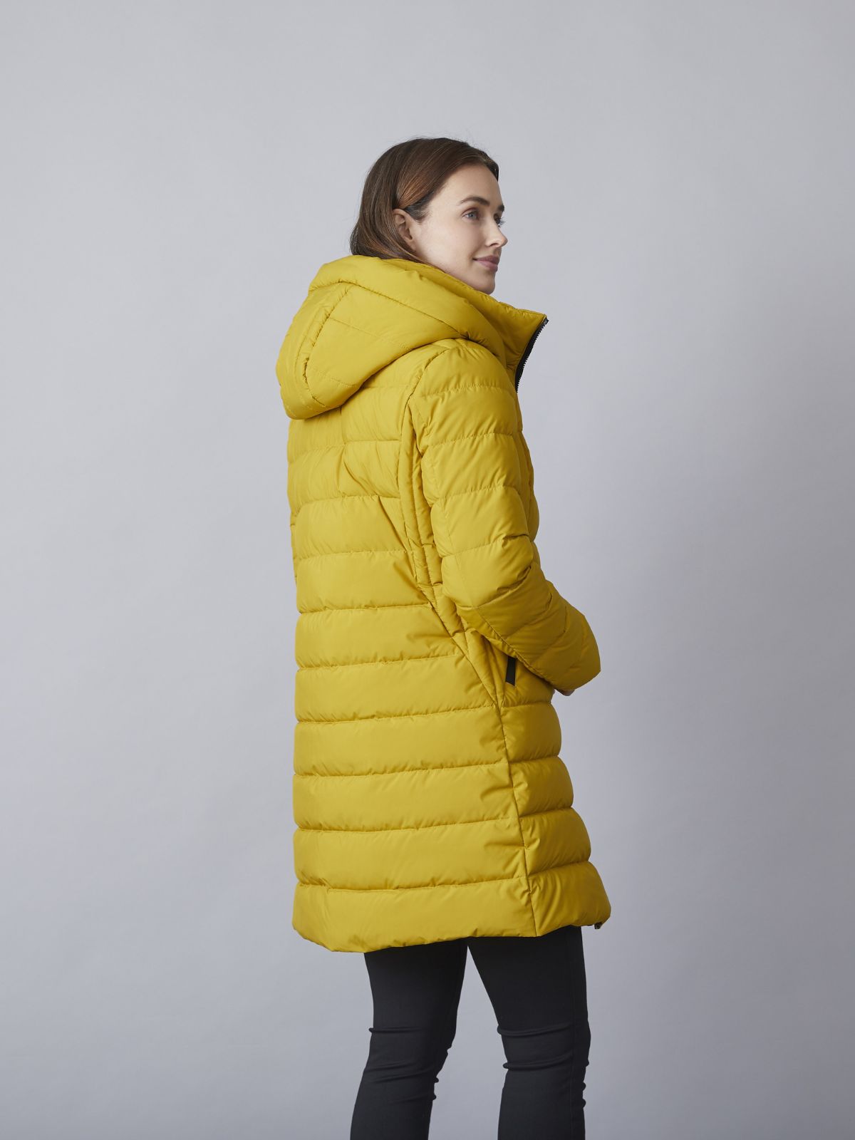 Model iført Kamilla kort overgangsjakke til damer i dijon med hætte, quiltet design og praktiske lommer.
